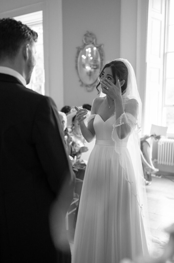 Black and white photo of the bride, Charlie, wiping away a tear as Martin read his vows.