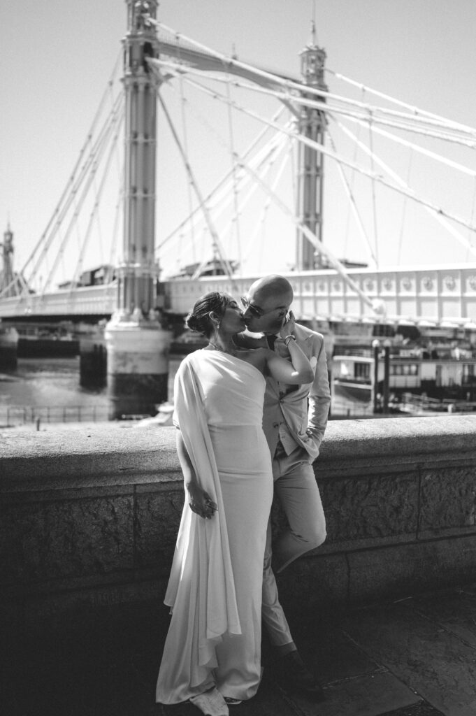 The bride and groom kisses with Albert Bridge and the London scenery in the background.