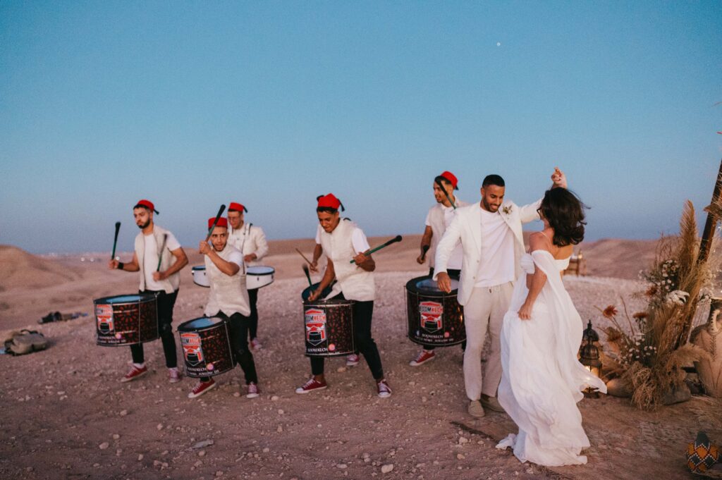 Traditional Moroccan performers adding cultural charm to Megan and James' Marrakech desert elopement with lively music and dancing, enhancing the romantic atmosphere designed by La Perle Events Marrakech Wedding Planner.