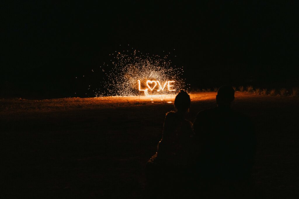 A vibrant shot of the fireworks display above the Agafay desert, spelling "LOVE" as Megan and James celebrate their elopement wedding, with event planning by La Perle Events Marrakech Wedding Planner and floral arrangements by The Bloom Room Marrakech.