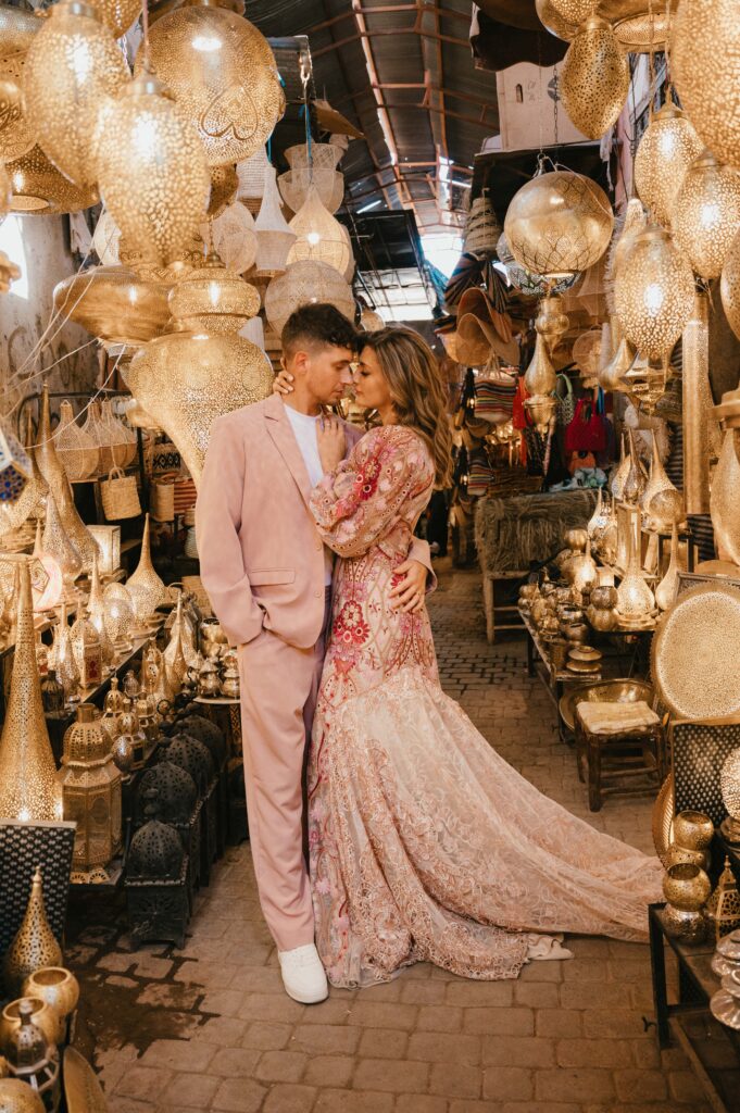Paul and Lisa’s elopement wedding in Marrakech, captured in the lively souk. One shot shows They stand inside a light-filled shop, surrounded by intricate Moroccan lanterns.